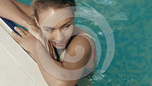 Girl in a swimsuit recline against the edge of the pool