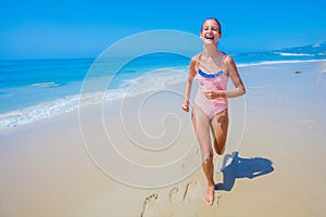 Girl in swimsuit runing and having fun on tropical beach