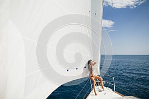 girl in swimwear on yacht under big white sail