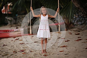 Girl on the swing on the beach in white dress