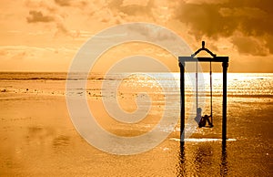 A girl on a swing over the sea at sunset in bali,indonesia photo