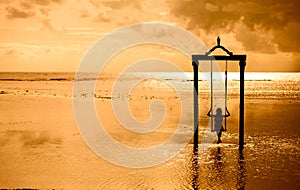 A girl on a swing over the sea at sunset in bali,indonesia 2 photo