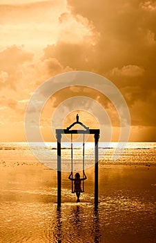 A girl on a swing over the sea at sunset in bali,indonesia 3 photo