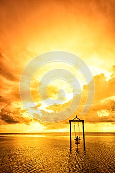 A girl on a swing over the sea at sunset in bali,indonesia 5 photo