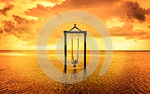 A girl on a swing over the sea at sunset in bali,indonesia 7 photo