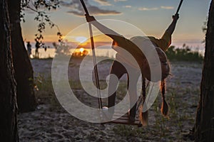 Girl on swing by sea in autumn sunset, family walk in nature, fall vibes, travel, active lifestyle