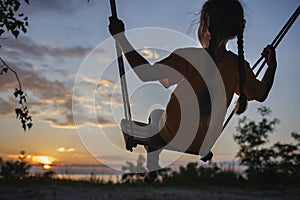 Girl on swing by sea in autumn sunset, family walk in nature, fall vibes, travel, active lifestyle
