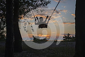 Girl on swing by sea in autumn sunset, family walk in nature, fall vibes, travel, active lifestyle