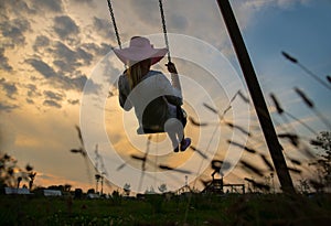 Girl on swing at sunset