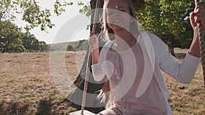 Girl swinging with a large smile on rope swing