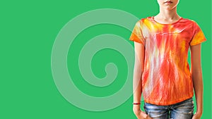 A girl in a t-shirt with tie dye style in the right side of the frame on a green background.