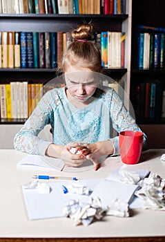 Girl at the table, in hands crumpling a piece of paper