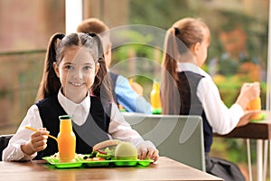 Girl at table with healthy food in school canteen photo