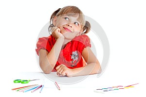 Girl at table with pencils, paints and scissors