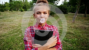 Girl with tablet pc blew up bubble from chewing gum