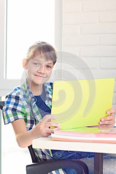 A girl with a tablet sits at a table at home and joyfully looked into the frame