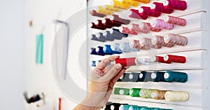 A girl tailor selects colored threads for tailor job. Close-up of hands