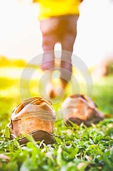 Girl take off her shoes. Child`s foot learns to walk on grass wi