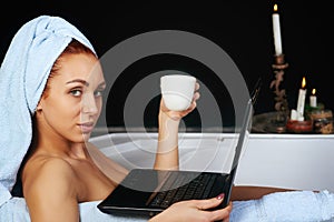 Girl takes a bath and is working with laptop