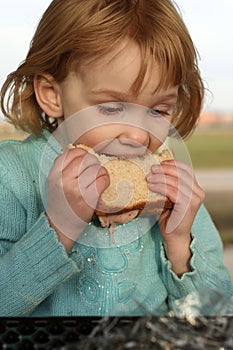 Girl takes big bite of sandwich
