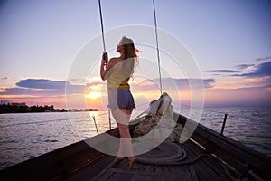 Girl takes a photo of sunset. Young woman meets sunrise on boat