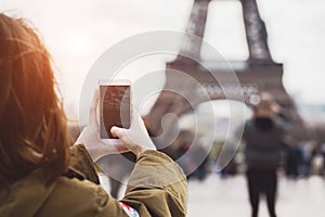 Girl takes a picture of the eiffel tower on  smartphone