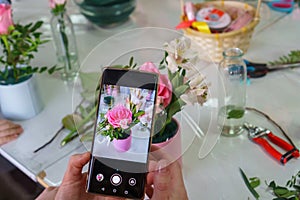 A girl takes a picture of a finished bouquet on her phone at a master class on making bouquets