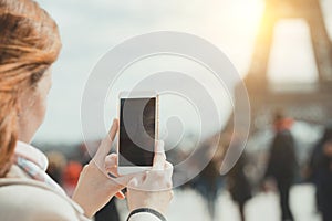 Girl takes pictures of a Eiffel Tower on a smartphone