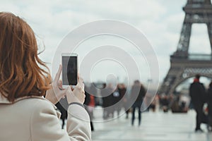 Girl takes pictures of a Eiffel Tower on a smartphone