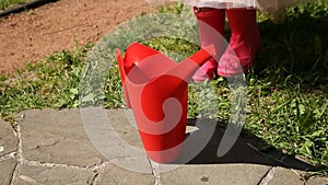 The girl takes a red watering can