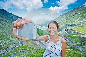 The girl takes a selfie photo of Transfagarasan mountain road. Romania.