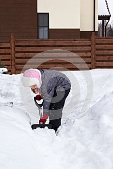 Girl takes snow off the track with a shovel