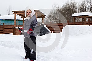 Girl takes snow off the track with a shovel