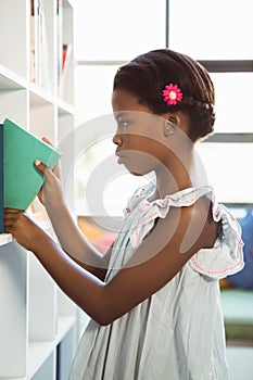 Girl taking a book from bookshelf in library