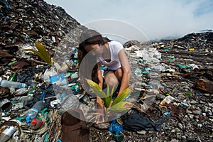 Girl taking care of plant on garbage dump