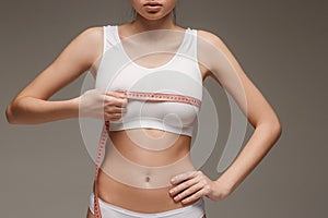 The girl taking measurements of her body, white background.