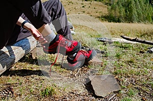 Girl taking off hiking shoes on camping during hiking in mountains