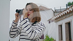 Girl taking old camera photos at whitewashed houses. Beautiful tourist travel