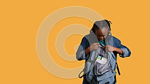 Girl taking out business class materials out of rucksack, studio background