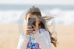 Girl taking photo with cellphone on the beach