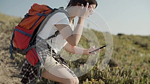 Girl taking photo with her phone while backpacking on sunny day.