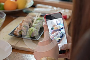 Girl taking a photo of a home made sushi plate with two different sushi rolls