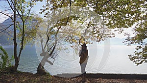 Girl taking a photo of mountain lake panorama