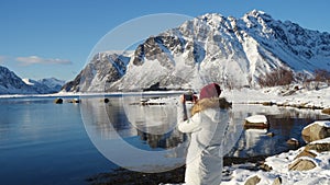 Girl taking a photo of sunny winter fjord
