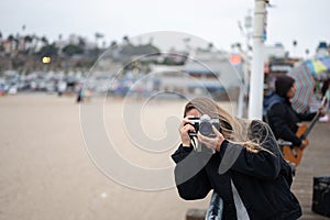 girl taking photos with her vintage camera at the Santa Monica pier