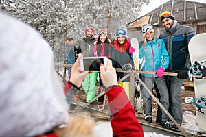 Girl taking pictures of cheerful friends on cold winter day