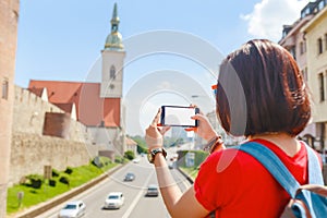 Girl taking pictures on her smartphone of St Martin Church in Bratislava, Slovakia