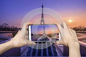 Girl taking pictures on mobile smart phone in eiffel tower