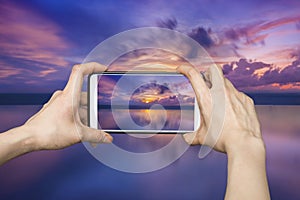 Girl taking pictures on mobile smart phone in sunset beach,Phuket,Thalland