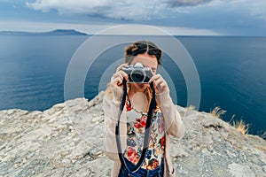 Girl taking pictures outdoors on a retro camera on a summer vacation
